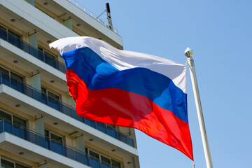 The flag of Russia is flying against the background of the building