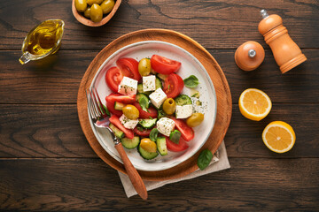 Greek salad. Fresh Greek salad with fresh vegetables, tomato, cucumber, green olives and feta cheese on old dark wooden table background. Top view.