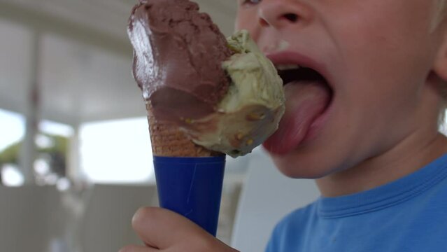 Close-up of a kid's ice cream ride. Chocolate and pistachio flavor, use waffle cone. Reflection of light surface of fatty ice cream dirty lips in bokeh. 7.10.2021 Borgagne, Puglia, Italy. 