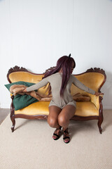Pensive Black woman relaxing on a gold couch