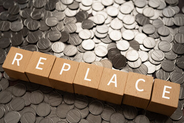 「REPLACE」と書かれた積み木とコイン
