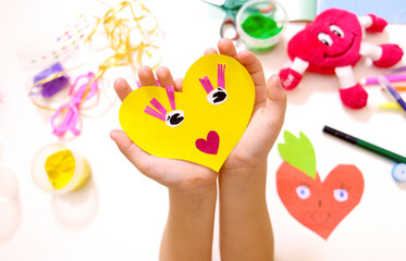 Child making funny crafts  from paper and clay, plasticine. Hearts  as gift for Mothers day, Fathers day, Birthday or Valentines day . Arts  crafts concept.