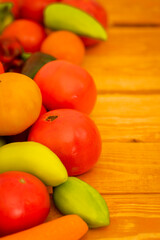 Bright ripe juicy vegetables on a wooden table: tomatoes, onions, carrots, paprika, sweet peppers, copy space, selective focus