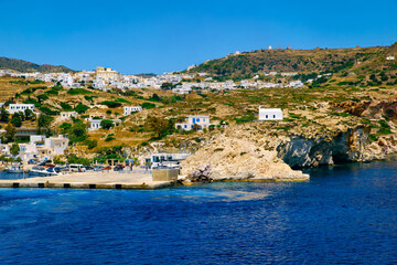 Fototapeta na wymiar Beautiful summer day of Greek island town by seafront. Whitewashed houses by waterfront. Mediterranean vacations. Milos, Cyclades, Greece.