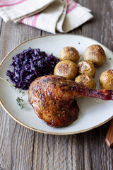 Baked duck leg with potatoes and red cabbage.