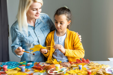 mother and daughter paint autumn leaves