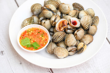 Cockles on white plate with seafood sauce on table background , Fresh raw shellfish blood cockle ocean gourmet seafood in the restaurant