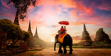 The tourists on an ride elephant tour of "Ayuthaya" the ancient city of Thailand in sunset background.