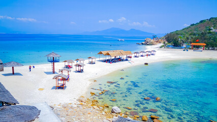 Fototapeta premium Double beach in the sea on the islands. Sunny day, turquoise transparent sea. A spit between two small islands. Lifeguard tower and beach gazebos. 