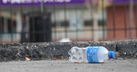 Empty plastic bottle thrown on ground on city street. Litter on ground. Recycle for eco-friendly cleanup.