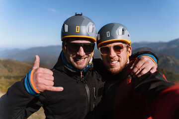 Portrait of two paragliders preparing for the flight on mountain, looking at camera. Extreme sports...