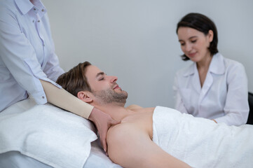 Fototapeta premium Young man having neck and shoulders massage in a spa salon