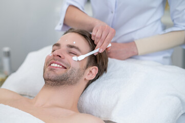 Obraz na płótnie Canvas Cosmetologist applying moisturizing cream on clients face