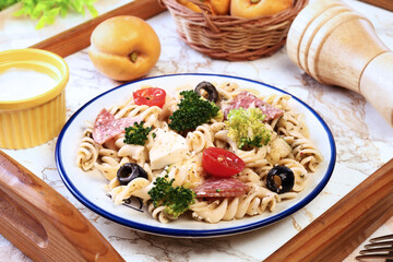 Pasta salad with tomatoes, ham, black olives, broccoli and cheese