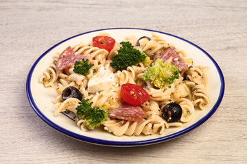 Pasta salad with tomatoes, ham, black olives, broccoli and cheese