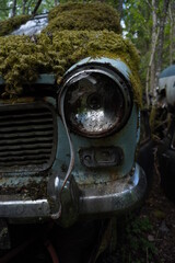 Fototapeta na wymiar mossy headlight of blue rusted car