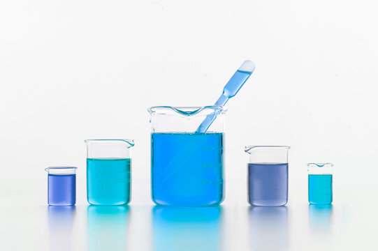Set of laboratory test flasks with blue liquids in white studio