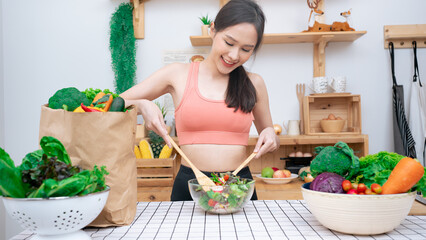 Asian Beautiful in sportswear learning to cook mix salad.Young beautiful girl sister feeling happy and enjoy eating fruits salad healthy foods to diet and lose weight for health care in house.