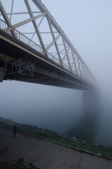 Young woman standing under the bridge on a misty winter day