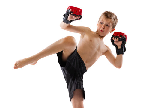One little boy, sportive kid in black shots and gloves training thai boxing on white studio background. Sport, education, action, motion concept.