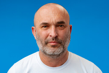 Fototapeta premium Portrait of a middle-aged man against blue background in studio