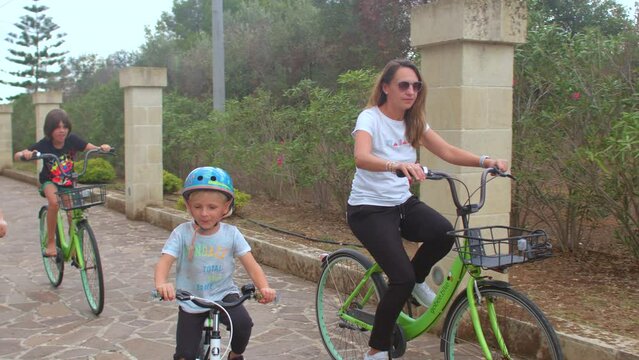 Active family lifestyle on vacation. They ride a bike, looking for adventure. Leisure activities on wheels. Movement along the stone road, exit. 8.10.2021 Borgagne, Puglia, Italy. 