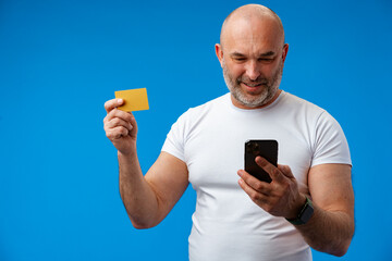Happy middle-aged man with a phone in his hands against blue background