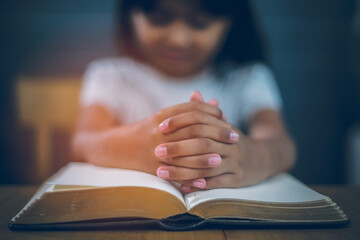 Asian Christian girl Both hands join together to pray and seek the blessings of God. She was reading the Bible and sharing the gospel in church. Concepts of Faith, Spirituality and Religion.