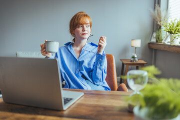 Shot of stressed business woman working from home on laptop looking worried, tired and overwhelmed. Businesswoman with headache in the office.........