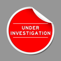 Red color peel sticker label with word under investigation on gray background