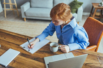 Smiling beauyiful teen girl preparing school homework, using laptop, happy black schoolgirl, pupil doing tasks, writing essay, studying at home, making notes, writing, reading textbooks....