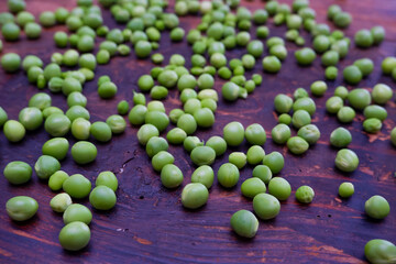 Fresh peeled green pease on a brown wooden table with copy space. Still life of green peas in pods with pea shoots on wooden table