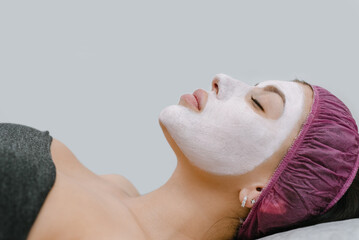 Portrait of young woman having facial peeling treatment in beauty salon