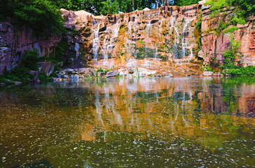 Fototapeta na wymiar Wide-angle landscape with waterfalls. Stones reflected in the water. Beautiful sunny day in the Sofievsky arboretum (Sofiyivsky Park) in Uman, Ukraine. Travel and tourism concept