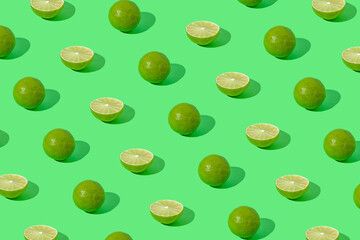Trendy pattern composition with sliced lime on bold green background. Citrus fruit wallpaper.