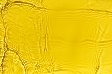 Waves on clear water surface, yellow abstract background.