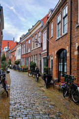 A peaceful cobbled alley  with bicycles parked outside traditional houses. Springtime in Haarlem, Netherlands.