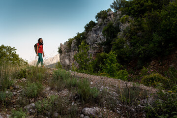 Naklejka na ściany i meble A young woman with a backpack looks at the valley