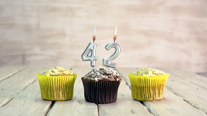 Happy birthday muffins with candles with the number 42. Card copy space with pies for...