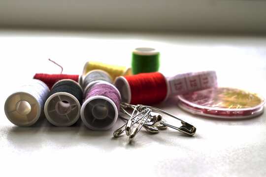 sewing kit thread needles pins and measuring tape on the table