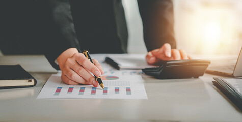 business woman or accountant who are using a calculator to calculate business data Accounting documents and laptop computer at the office business idea