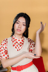 Stylish asian model in retro clothes posing on orange background.