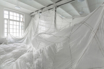 Art installation with a white parachute hanging in the huge white photo studio.