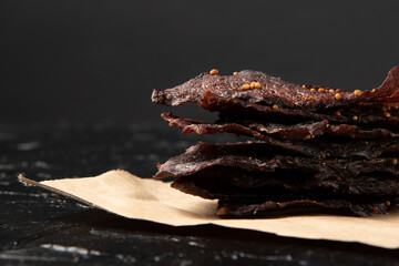 Veal jerky on craft paper and black background.
