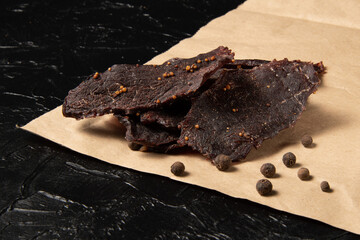 Veal jerky on craft paper and black background.