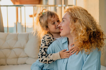 close-up portrait happy mother with daughter at home on the balcony sitting in a hammock chair, sunny evening at sunset during the golden hour