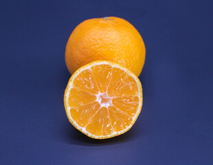 Tangerine or kamala slice and whole on black background, selective focus