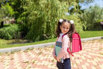 Smiling little cute schoolgirl in uniform with school bag, backpack, back to school, 1 september