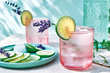 Cool lavender lemonade with lime slices and lavender flower on the table near pastel light blue...