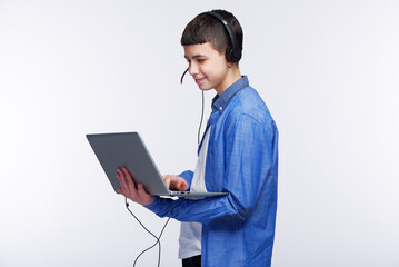 Young teenage boy using his laptop , finishing his schoolwork or listening to an online class